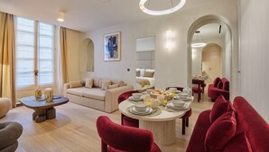 Una sala de estar moderna con comedor, que presenta una mesa redonda dispuesta para el desayuno, un sofá y una silla roja.