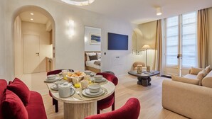Una habitación de hotel moderna con comedor, sala de estar y dormitorio.