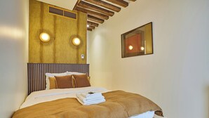 Una habitación de hotel con cabecera de madera, cama con ropa de cama marrón y un espejo en la pared.