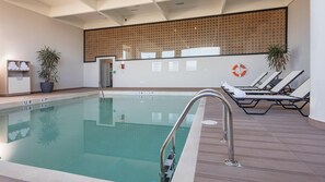 A swimming pool with clear water, a metal ladder, and lounge chairs with towels. - Holiday Inn & Suites Aguascalientes (Aguascalientes)
