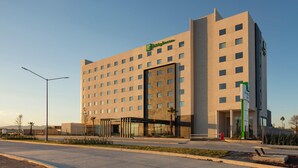 A modern hotel with a prominent 'Holiday Inn' sign, multiple floors, and a covered entrance. - Holiday Inn & Suites Aguascalientes (Aguascalientes)