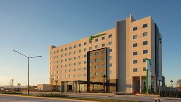 Un hotel moderno con un llamativo letrero de 'Holiday Inn', varios pisos y una entrada cubierta.