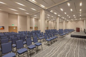 A conference room with rows of chairs, a stage, and a carpeted floor. - Holiday Inn & Suites Aguascalientes (Aguascalientes)