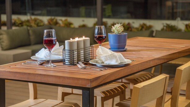 A wooden dining table with candles, wine glasses, and a potted plant. - Holiday Inn & Suites Aguascalientes (Aguascalientes)