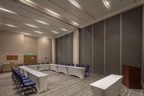 A conference room with a long table, chairs, a podium, and a wooden cabinet. - Holiday Inn & Suites Aguascalientes (Aguascalientes)