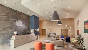 A modern hotel lobby with a reception desk, seating area, and a large potted plant. - Holiday Inn & Suites Aguascalientes (Aguascalientes)