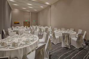 A conference room with multiple round tables, white chairs, and neatly arranged tables with glassware and cutlery. - Holiday Inn & Suites Aguascalientes (Aguascalientes)