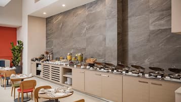 Una barra de desayuno moderna con un fondo de pared de mármol, armarios de madera y una variedad de alimentos para el desayuno.