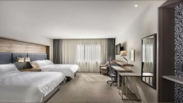 Habitación de hotel con dos camas, un escritorio, una silla, un espejo y una ventana con cortinas.