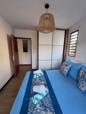 A bedroom with a bed, a hanging light fixture, a window with blinds, and a door leading to another room. - Perfect Moorea Getaway for Families & Friends – Pool + Beach 200m (Moorea)