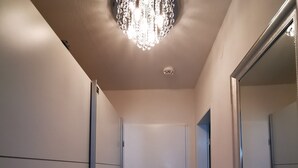 En hall med en kristallkrona, en dörr och en spegel.