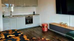 Ett modernt kök med gråa skåp, en inbyggd ugn och en stor platt-TV som är monterad på väggen.