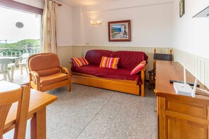 Ein gemütliches Zimmer mit einem roten Sofa, einem Holzstuhl, einem Holztisch und einem Laptop.