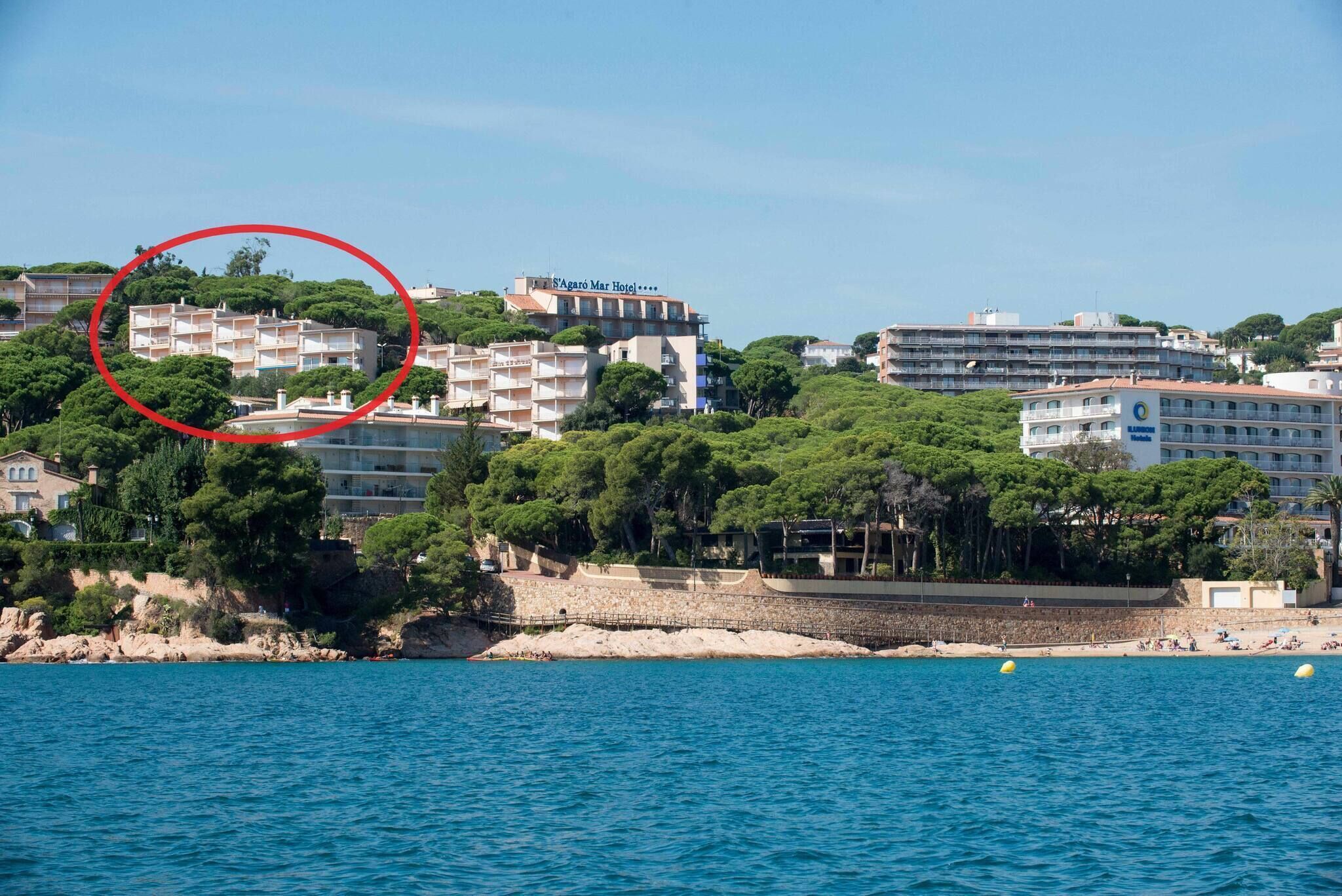 Um hotel à beira-mar com vários edifícios, praia e vista clara do oceano.
