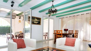 A modern living room with white sofas, a glass coffee table, and a dining area with a wooden table and chairs. - 08.00 Mirador House. Private pool (Platja d´Aro)