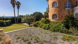 A stone building with a circular tower, surrounded by greenery and palm trees. - 08.00 Mirador House. Private pool (Platja d´Aro)