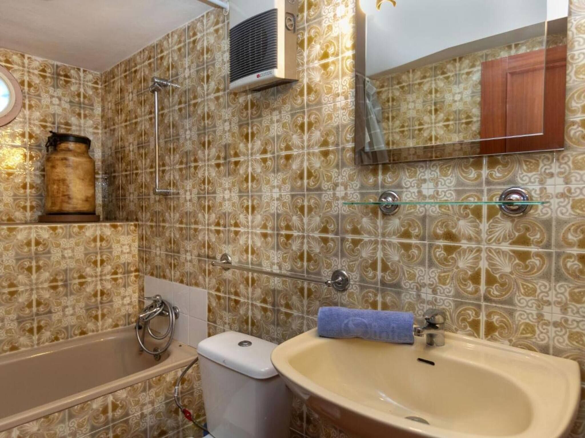 Un baño con baldosas estampadas, una bañera, un inodoro, un lavabo y un espejo.