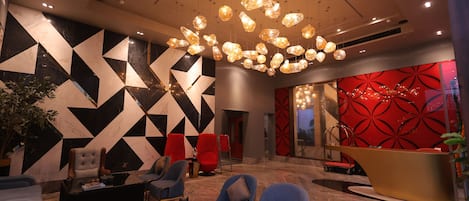 Una hall con un design geometrico alla parete, una reception e un'accogliente disposizione di sedute moderne.