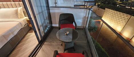 A balcony with a glass railing, a small round table, and a red cushioned bench.