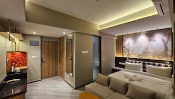 A modern hotel room with a bed, a sofa, a small table, and a large wall mural.