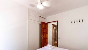 A bedroom with a bed, a ceiling fan, a wooden door, and a wall-mounted light fixture. - 24.40 Carrilet 37 pis  S'Agaró Nice apartment (Sant Feliu de Guixols)