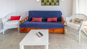 A cozy room with a blue sofa, two white wicker chairs, a white coffee table, and a wall-mounted board game. - 24.40 Carrilet 37 pis  S'Agaró Nice apartment (Sant Feliu de Guixols)