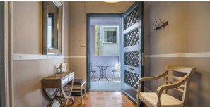 Un couloir avec un bureau, une chaise et une vue sur une pièce où se trouvent une table et des chaises.