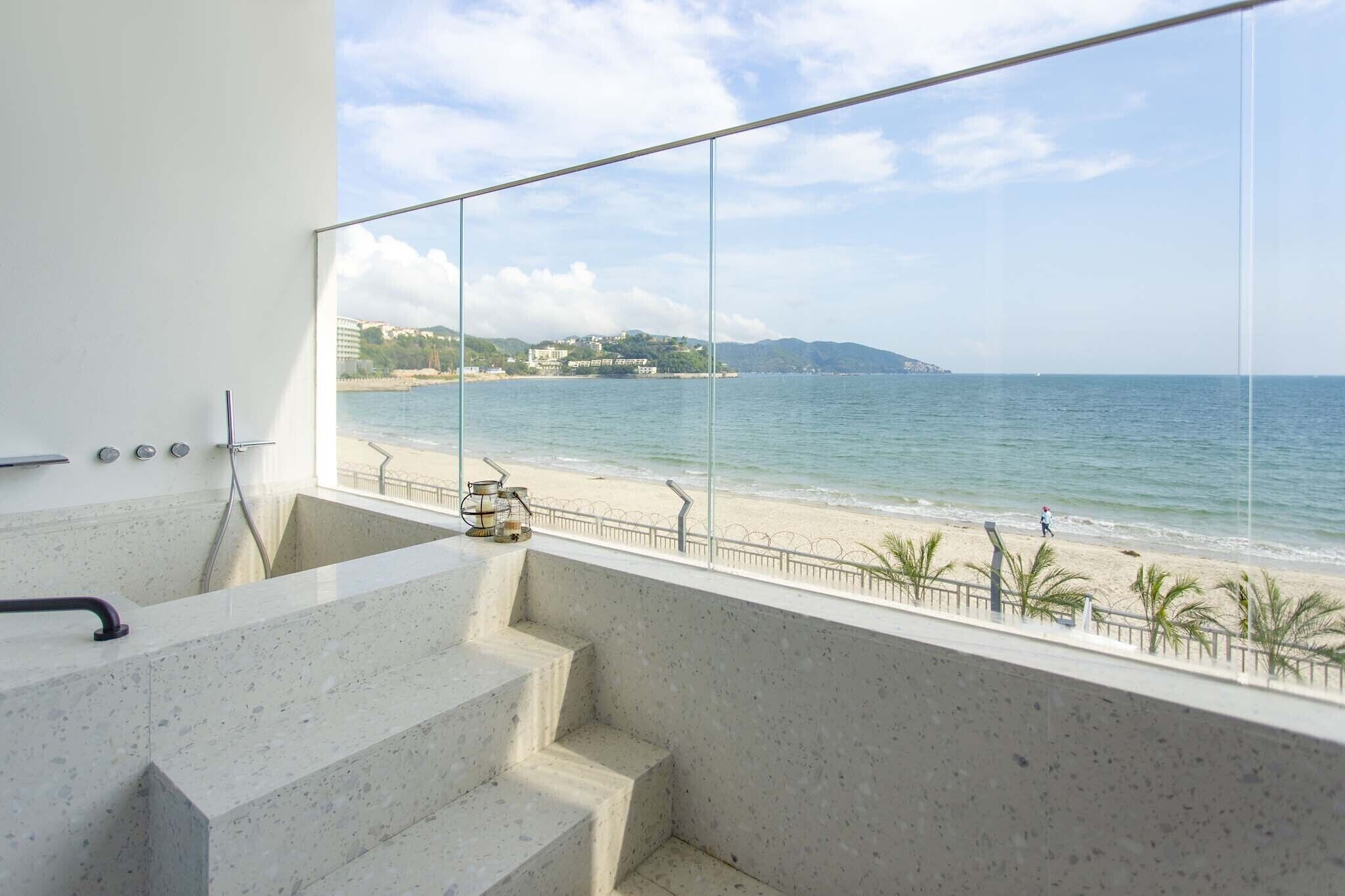 A bathroom with a large window overlooking a beach.