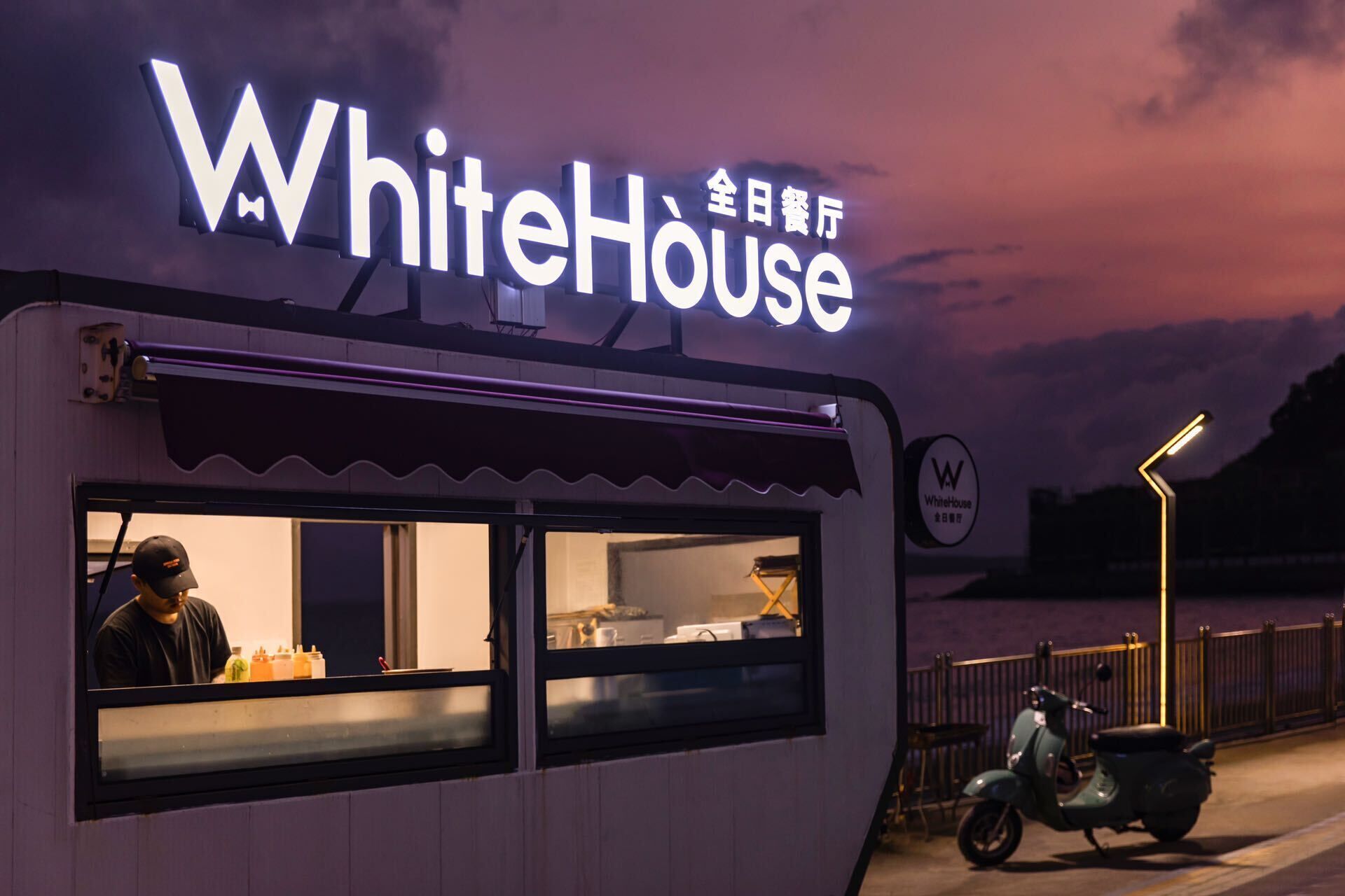 A food truck named WhiteHouse with a neon sign, a person inside, and a scooter parked outside.