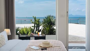 A hotel room with a bed, a desk, and a view of the beach and sea.