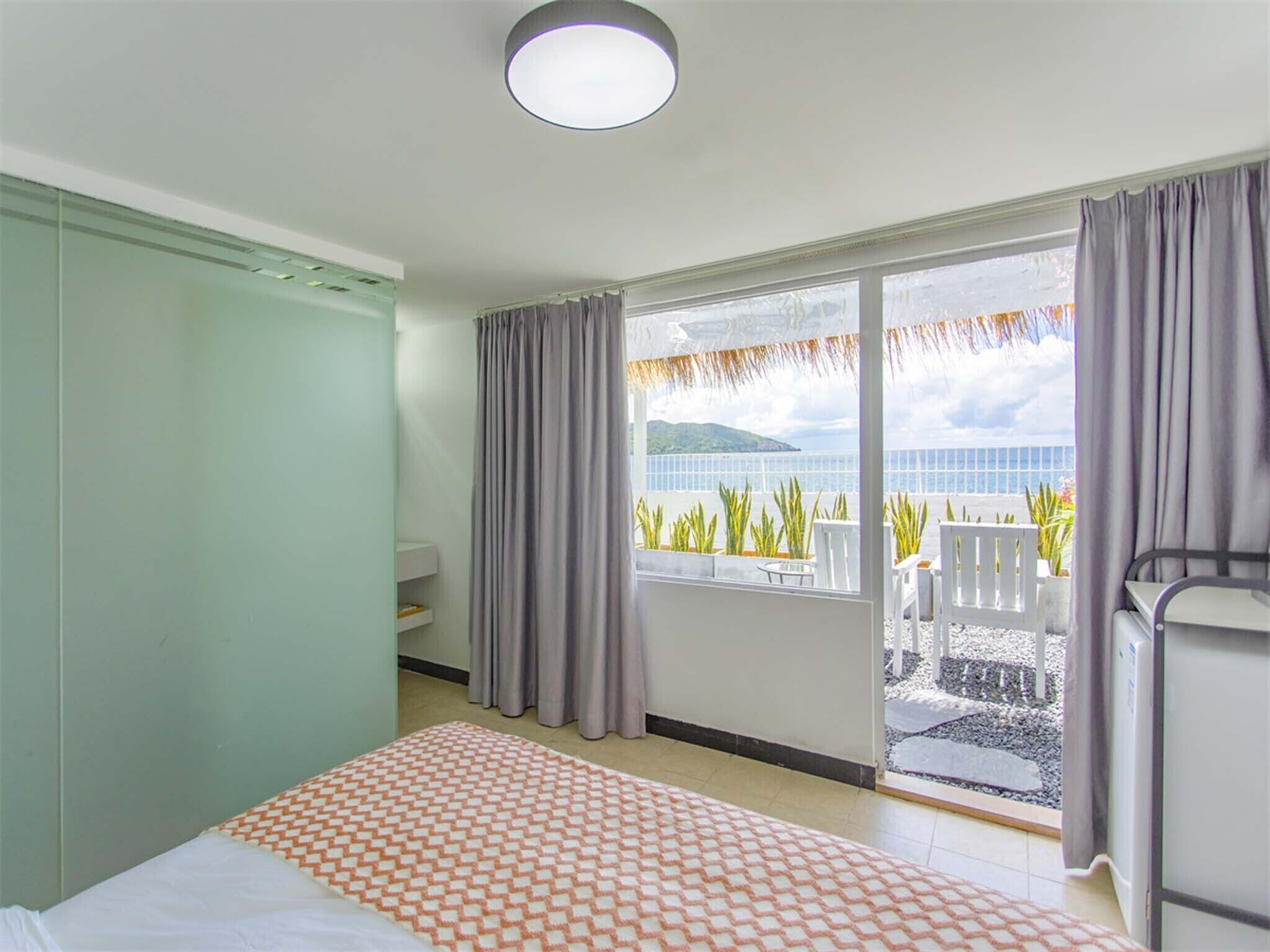 Une chambre d’hôtel avec un lit, une petite table, une chaise et un balcon donnant sur la mer.