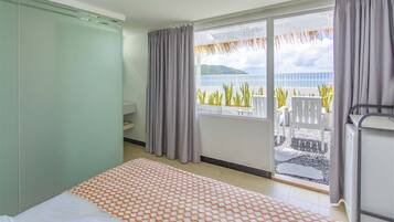 Une chambre d’hôtel avec un lit, une petite table, une chaise et un balcon donnant sur la mer.
