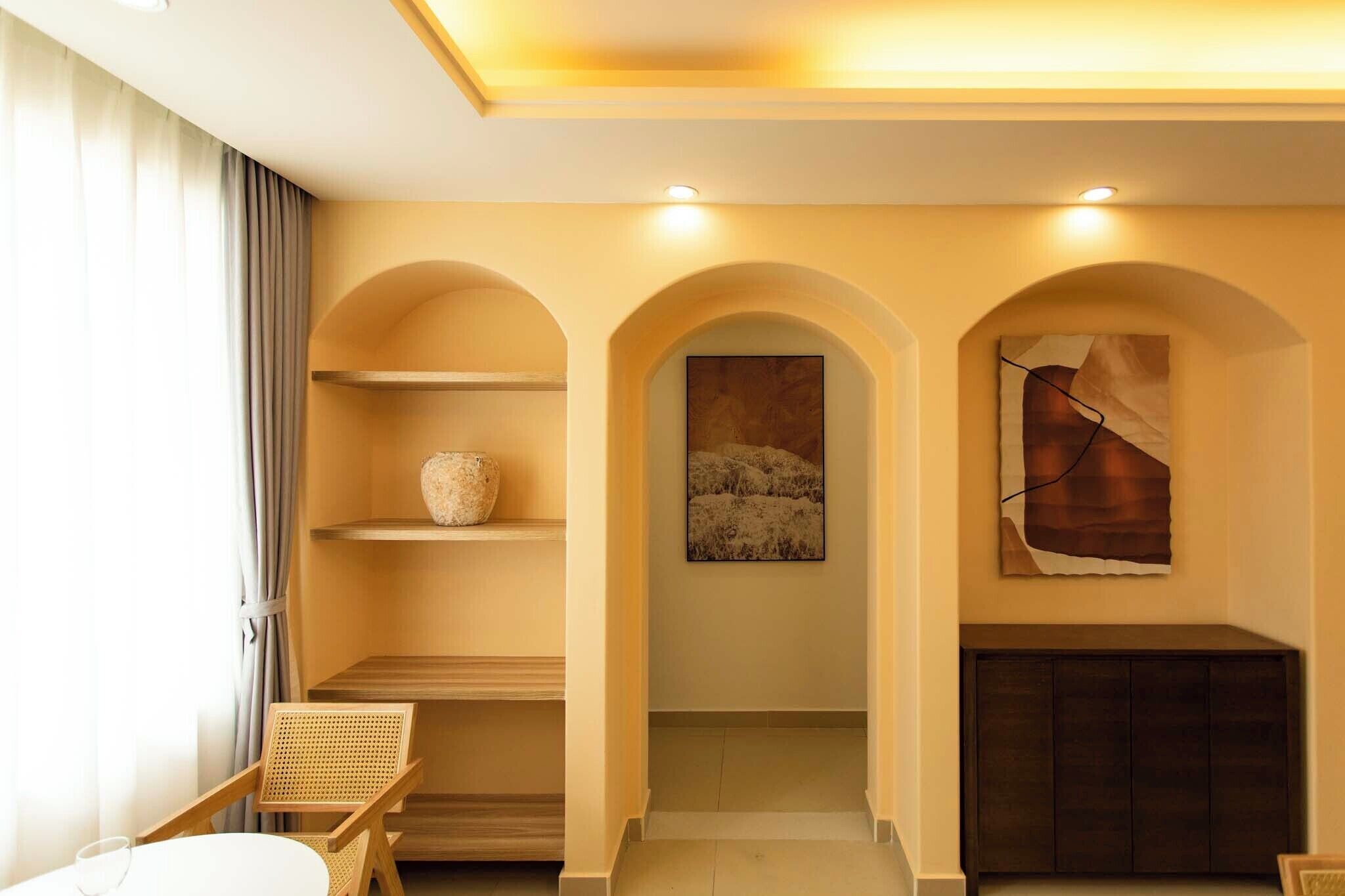 A hotel room with a sofa, a coffee table, a bookshelf, and a painting on the wall.