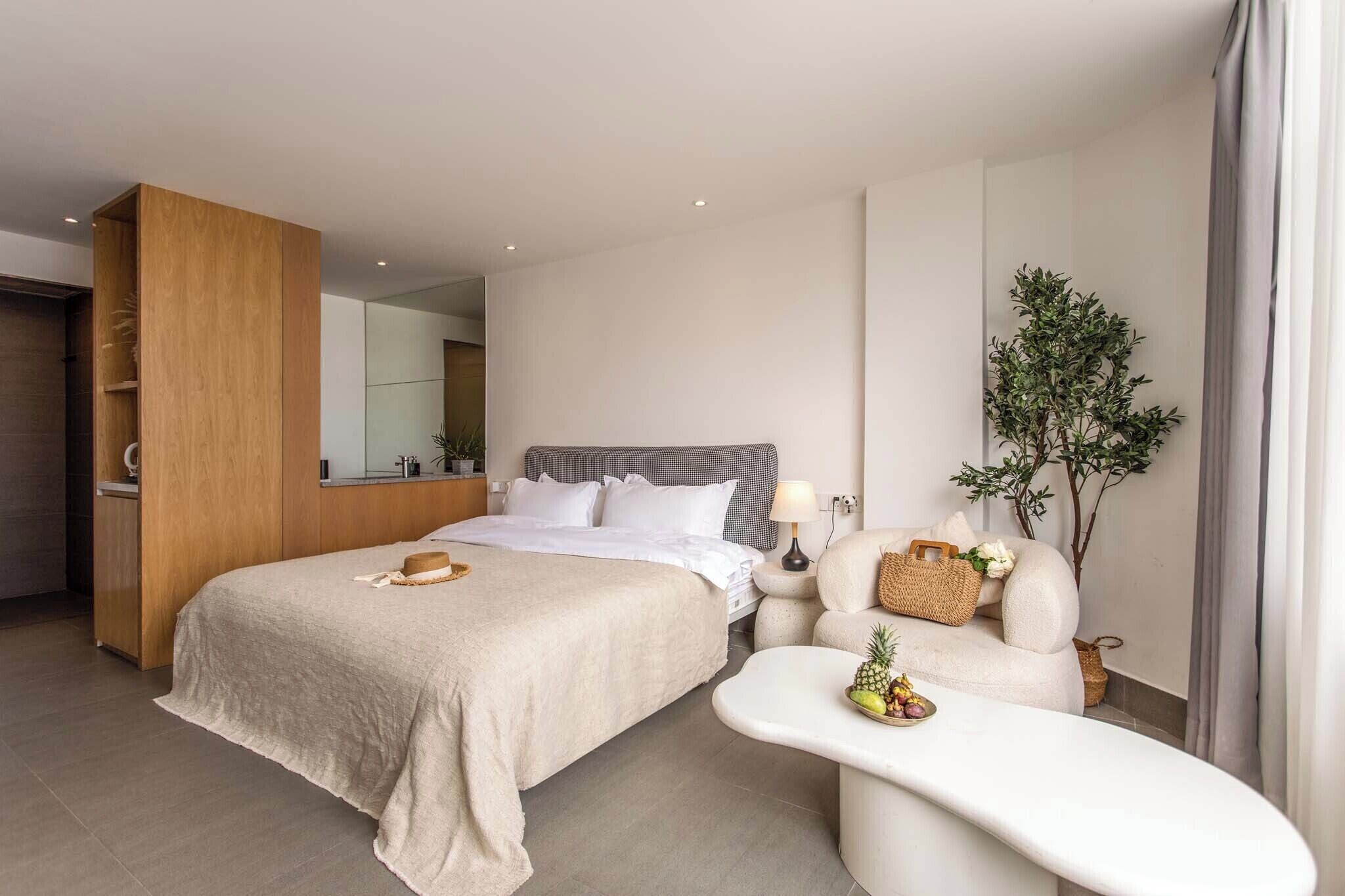 A modern hotel room with a large bed, a sitting area with a small table, and a large mirror.