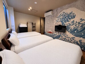 Ein Hotelzimmer mit zwei Betten, einem an der Wand befestigten Fernseher und einem großen Wandbild mit Wellenmuster.