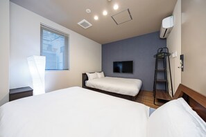 Habitació d'hotel amb dos llits, televisió, finestra amb persianes, aire condicionat i una escala.