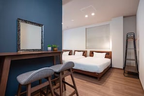 Habitación de hotel con escritorio, dos camas individuales, un espejo y una escalera.