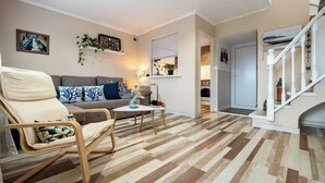 Ein Wohnzimmer mit einer Couch, einem Sessel, einem kleinen Tisch und einer Treppe.