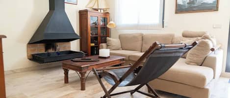 Una sala de estar con chimenea, un sofá, una mesa y una silla plegable.