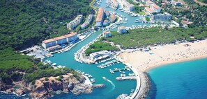 An aerial view of a coastal marina with boats, a beach, and buildings. - 05.70 Marina Port D'Aro terraced house (Platja d´Aro)