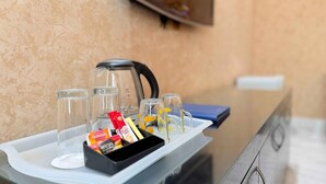 Un plateau avec une cafetière, quatre verres et une boîte de sachets de café instantané.