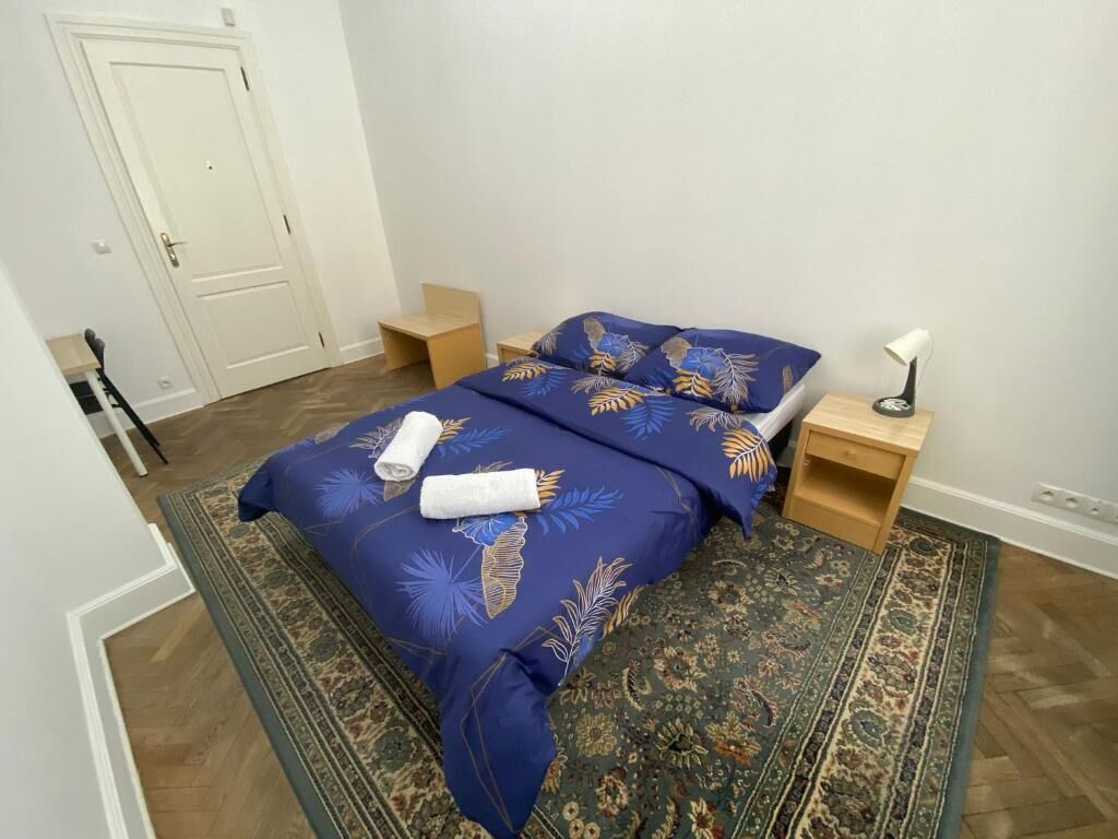 A bedroom with a bed, two nightstands, a door, and a patterned rug.