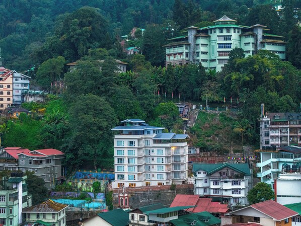 A hillside residential area with multi-story buildings, some with balconies, surrounded by dense greenery. - Sterling Mount Olive Gangtok (Gangtok)