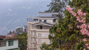 A multi-story building with balconies, a sign indicating 'Stesling Mount Olive Gangtok', and a mountainous backdrop. - Sterling Mount Olive Gangtok (Gangtok)