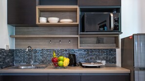 A modern kitchen with a stainless steel sink, a microwave, and a refrigerator. - Oxavia Garden Bungalow B1-B2 (Rawai)