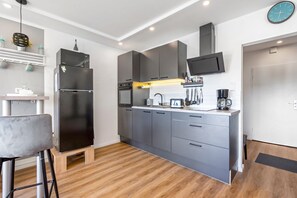 A modern kitchen with grey cabinetry, a built-in oven, a microwave, and a coffee maker.