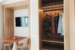 Une pièce avec une armoire en bois, un téléviseur fixé au mur et une table avec des chaises.