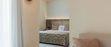 Een hotelkamer met een bed, nachtkastje, lamp en een sofa.