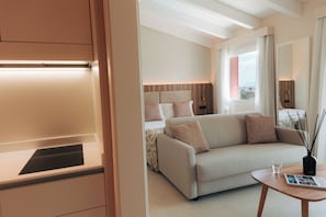 Une chambre d’hôtel moderne, équipée d’un canapé, d’une table de chevet, d’une lampe et d’une fenêtre donnant sur un beau paysage.