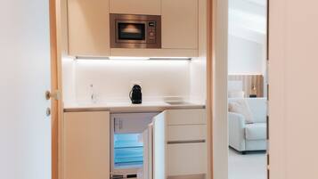 A compact kitchenette with a microwave, a coffee maker, and a built-in dishwasher.